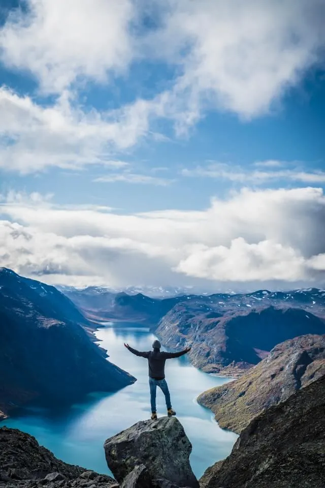 Person on rock formation near mountains