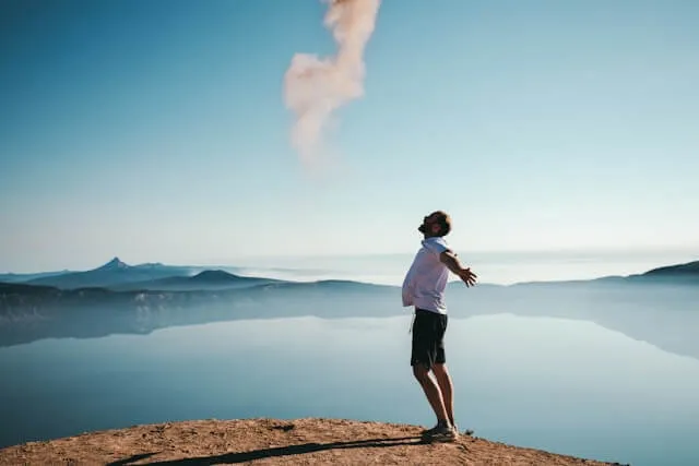 Person standing on sand beside calm water